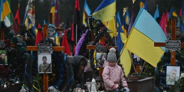 LVIV, UKRAINE - JANUARY 06: Family members visit the graves of their loved ones killed during Russia-Ukraine war at Lychakiv Cemetery during Orthodox Christmas Eve, in Lviv, Ukraine, on January 6, 2023. 