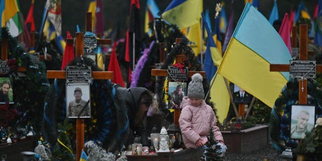 LVIV, UKRAINE - JANUARY 06: Family members visit the graves of their loved ones killed during Russia-Ukraine war at Lychakiv Cemetery during Orthodox Christmas Eve, in Lviv, Ukraine, on January 6, 2023.