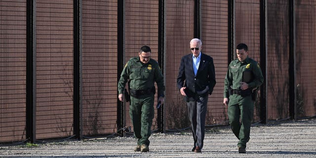 US President Joe Biden speaks to a US Border Patrol officer as they walk along the US-Mexico border fence in El Paso, Texas, January 8, 2023. 