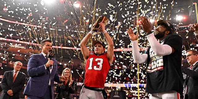Quarterback Stetson Bennett (13) of the Georgia Bulldogs holds up the championship trophy after defeating the TCU Horned Frogs 65-7 to win the CFP national championship at SoFi Stadium in Inglewood Jan.  9, 2023. 