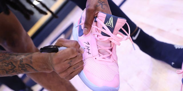 Ja Morant signs his shoes for a fan