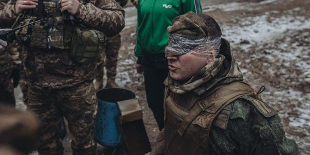 DONETSK, UKRAINE - JANUARY 12: Ukrainian soldiers frisk a Russian soldier captured on the Donbas frontline in Donetsk, Ukraine on January 12, 2023.