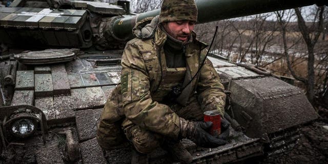 Een Oekraïense militair houdt een zelfgemaakte loopgraafkaars vast om geïmproviseerde schuilplaatsen aan te steken en te verwarmen, zittend op een tank aan de frontlinie nabij Kreminna, in de regio Lugansk, op 12 januari 2023, tijdens de Russische invasie van Oekraïne. 