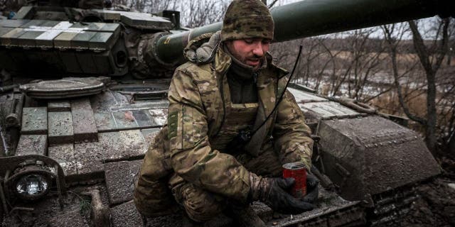 A Ukrainian serviceman holds a homemade trench candle to light and heat makeshift shelters, sitting on a tank on the frontline near Kreminna, Lugansk region, on January 12, 2023, amid the Russian invasion of Ukraine. 