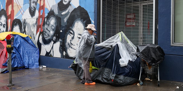 Homeless tents and a homeless woman are seen near the Tenderloin District during rainy day in San Francisco on January 13, 2023, as atmospheric river storms hit California, United States. 