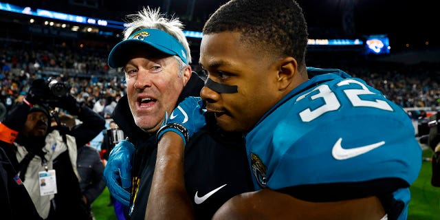 Tyson Campbell #32 of the Jacksonville Jaguars hugs head coach Doug Pederson after beating the Los Angeles Chargers in an NFL Wild Card Playoff football game at TIAA Bank Field on January 14, 2023 in Jacksonville, Florida. 