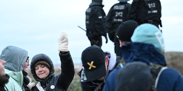 Climate activist Greta Thunberg (2nd from left) stands with other activists between Keyenberg and Lützerath under police surveillance at the open pit mine and dances. 