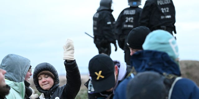 Climate activist Greta Thunberg (2nd from left) stands with other activists between Keyenberg and Lützerath under police surveillance at the open pit mine and dances. 