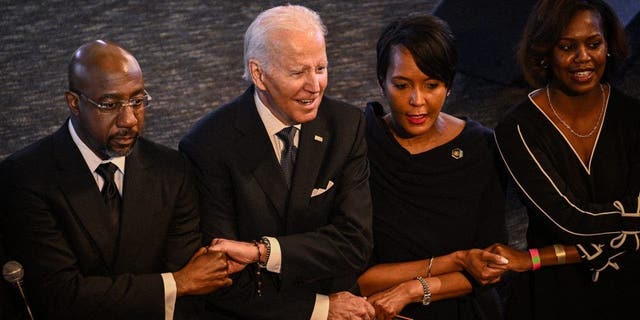 President Joe Biden houdt de hand vast van senator Raphael Warnock, de predikant van de Ebenezer Baptist Church, tijdens een eredienst in Atlanta, Georgia, op 15 januari 2023, de vooravond van de nationale feestdag ter ere van Martin Luther King Jr.