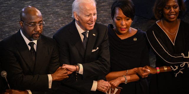 President Joe Biden holds hands with Sen. Raphael Warnock, the pastor at Ebenezer Baptist Church, during a worship service in Atlanta, Georgia, on Jan. 15, 2023, the eve of the national holiday honoring Martin Luther King Jr.