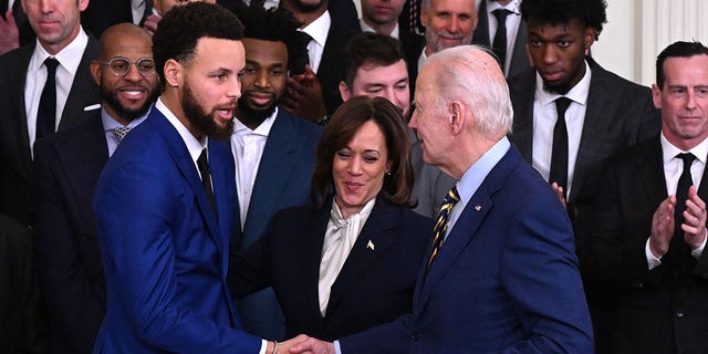 El presidente Biden le da la mano al jugador de baloncesto de los Golden State Warriors, Stephen Curry, a la izquierda, mientras la vicepresidenta Kamala Harris observa durante una celebración del Campeonato de la NBA Golden State Warriors 2022 en el Salón Este de la Casa Blanca en Washington, DC, el 17 de enero de 2023. 