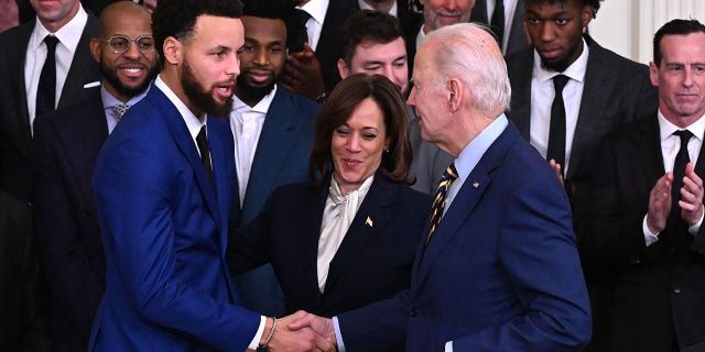 President Biden shakes hands with Golden State Warriors basketball player Stephen Curry, left, as Vice President Kamala Harris looks on during a celebration for the Golden State Warriors 2022 NBA championship in the East Room of the White House in Washington, D.C., Jan. 17, 2023.
