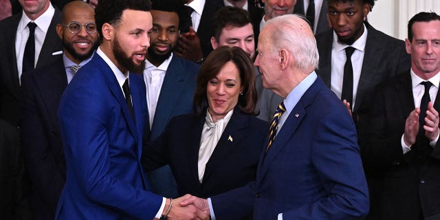 El presidente Biden le da la mano al jugador de baloncesto de los Golden State Warriors, Stephen Curry, a la izquierda, mientras la vicepresidenta Kamala Harris observa durante una celebración del Campeonato de la NBA Golden State Warriors 2022 en el Salón Este de la Casa Blanca en Washington, DC, el 17 de enero de 2023. 