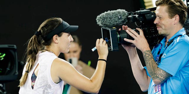 Jessica Pegula signs on the camera lens.