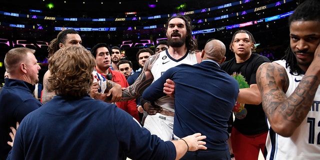 LOS ANGELES, CA - JANUARY 20: Steven Adams, #4 of the Memphis Grizzlies, is restrained by team trainers and assistant coaches as he has words with Shannon Sharpe following a verbal altercation with Ja Morant, #12 of the Memphis Grizzlies, and his father, Tee Morant, during the halftime against the Los Angeles Lakers at Crypto.com Arena on January 20, 2023, in Los Angeles, California. 