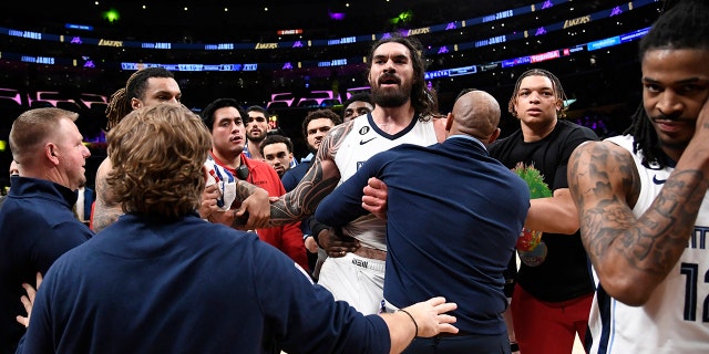 LOS ANGELES, CA - JANUARY 20: Steven Adams, #4 of the Memphis Grizzlies, is restrained by team coaches and assistant coaches as he talks to Shannon Sharpe following a verbal altercation with Ja Morant, #12 of the Memphis Grizzlies , and their father, Tee Morant, during halftime against the Los Angeles Lakers at Crypto.com Arena on January 20, 2023 in Los Angeles, California. 