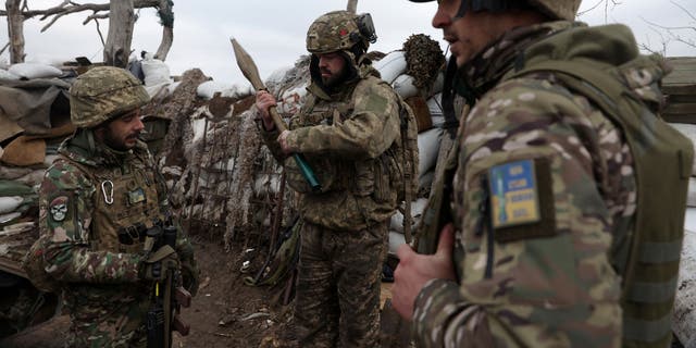 Ukrainian servicemen examine an RPG rocket as they stand in a trench on a frontline position in the Donetsk region on January 23, 2023, amid the Russian invasion of Ukraine. 