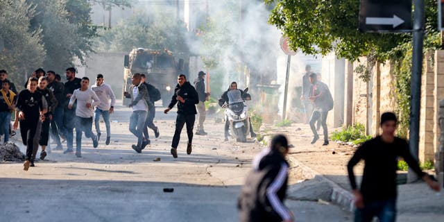 Palestinians run for cover during confrontations with Israeli forces in the occupied-West Bank city of Jenin, on January 26, 2023. (ZAIN JAAFAR/AFP via Getty Images)