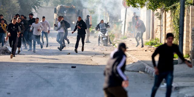 Palestinians run for cover during confrontations with Israeli forces in the occupied-West Bank city of Jenin, on January 26, 2023. (ZAIN JAAFAR/AFP via Getty Images)