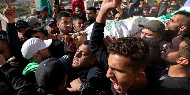Mourners carry the body of Palestinian youth Yusef Muhaisen, killed by Israeli fire amid clashes, during his funeral in the West Bank town of Al-Ram on Jan. 27, 2023.