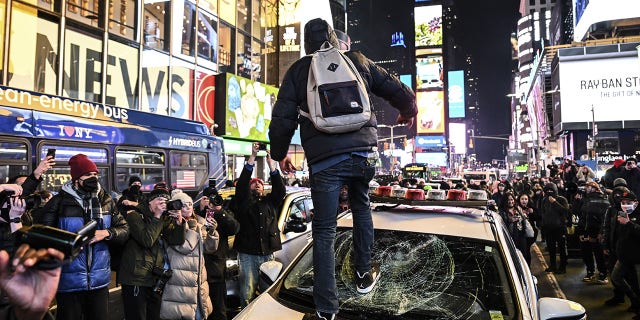 A protester is seen smashing the windows of a police car during the protest against the police assault of Tyre Nichols at Times Square in New York on Jan. 27, 2023.