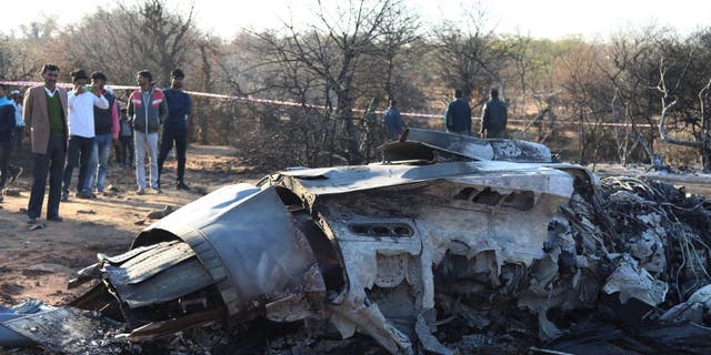 People stand next to a plane wreckage after a Sukhoi Su-30 and a Dassault Mirage 2000 fighter jets crashed during an exercise in Pahadgarh area some 30 miles from Gwailor on Jan. 28, 2023. 