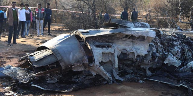 La gente se para junto a los restos de un avión después de que dos aviones de combate Sukhoi Su-30 y Dassault Mirage 2000 se estrellaran durante un ejercicio en el distrito de Pahadgarh, a 30 millas de Gwailor el 28 de enero de 2023. 