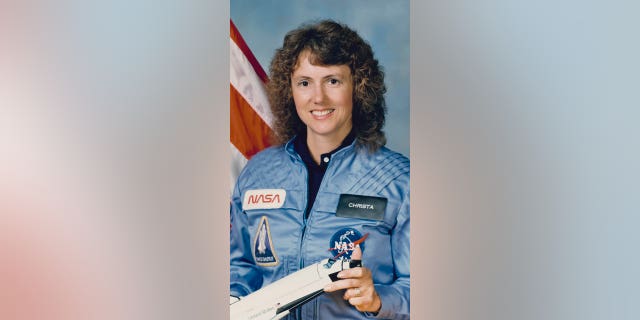 Christa McAuliffe (1948-1986), wearing a blue NASA jumpsuit, smiles in a studio portrait while holding a model of a space shuttle at Johnson Space Center in Houston, Texas, on Sept. 26, 1985. She was the first private citizen to go into space on the shuttle.