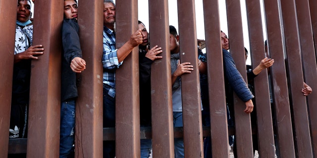 Immigrants wait for soup donated by the Yuma County Abolition group after crossing the border from Mexico on May 23, 2022, in San Luis, Arizona.