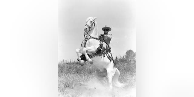 Clayton Moore (1914-1999), U.S. actor, in costume as he sits on his horse, Silver, which rears up in a publicity still issued for the television series, "The Lone Ranger," circa 1950. The series starred Moore as Lone Ranger.