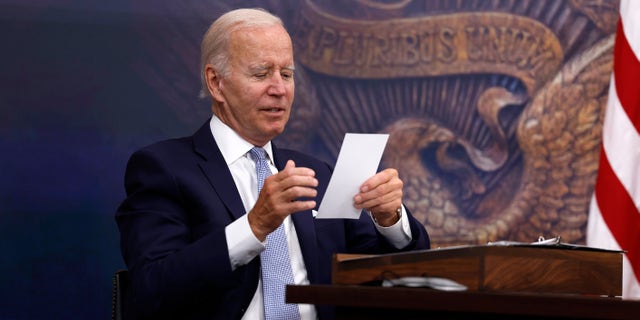 President Biden reads a note from an aide during a White House meeting on July 28, 2022.