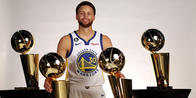 Stephen Curry of the Golden State Warriors poses with the four Larry O'Brien championship trophies he has won with the Warriors during Warriors Media Day Sept. 25, 2022, in San Francisco. 