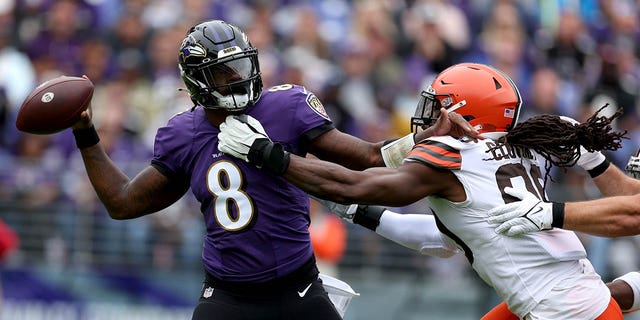Quarterback Lamar Jackson, #8 of the Baltimore Ravens, gets off a pass while being pressured by defensive end Jadeveon Clowney, #90 of the Cleveland Browns, in the first half at M&amp;T Bank Stadium on October 23, 2022, in Baltimore, Maryland. 