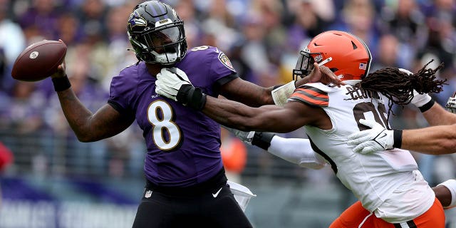 Quarterback Lamar Jackson, #8 of the Baltimore Ravens, receives a pass while being pressured by defensive end Jadeveon Clowney, #90 of the Cleveland Browns, in the first half at M&T Bank Stadium on October 23, 2022, in Baltimore. Maryland.