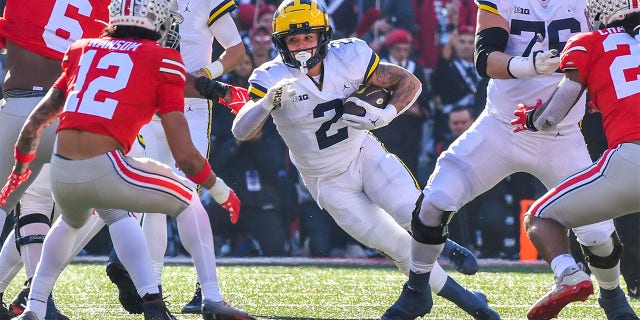 Blake Corum #2 of the Michigan Wolverines runs with the ball as Lathan Ransom #12 of the Ohio State Buckeyes prepares to tackle him during the first half of a college football game at Ohio Stadium on Nov. 26, 2022 in Columbus, Ohio.