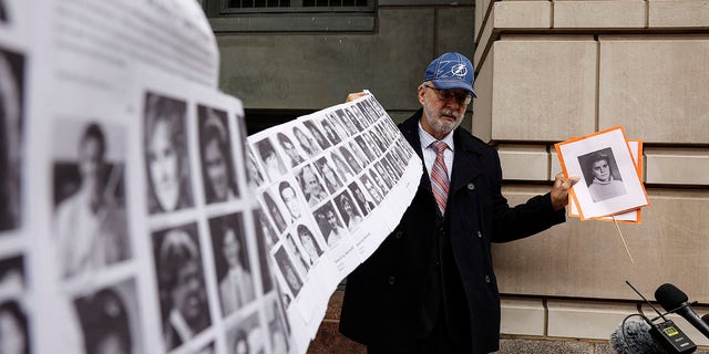 Paul Hudson, whose daughter Melina was one of the victims of the Pan Am Flight 103 bombing at Lockerbie, holds a banner with photos of other victims outside a federal courthouse ahead of the trial of the Libyan accused of making the bomb that blew up the plane.  December 12, 2022 Washington DC 