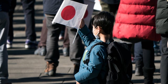 A boy holds a Japanese national flag during the New Year's appearance by the Japanese royal family at the Imperial Palace on January 2, 2023, in Tokyo, Japan.