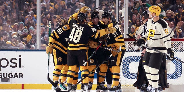 El número 74 de los Boston Bruins, Jake DeBrusk, celebra con sus compañeros de equipo después de marcar un gol contra los Pittsburgh Penguins en el tercer período del Discover NHL Winter Classic 2023 en Fenway Park el 2 de enero de 2023 en Boston, Massachusetts. 