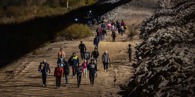 YUMA, ARIZONA - DECEMBER 30: Immigrants walk along the U.S.-Mexico border barrier on their way to await processing by the U.S. Border Patrol after crossing from Mexico on December 30, 2022 in Yuma, Arizona. (Photo by Qian Weizhong/VCG via Getty Images)
