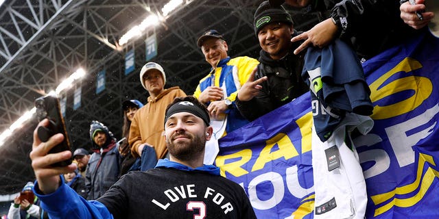 Baker Mayfield #17 of the Los Angeles Rams takes a selfie with fans prior to the game against the Seattle Seahawks at Lumen Field on January 08, 2023 in Seattle, Washington. Mayfield is wearing a t-shirt honoring Damar Hamlin #3 of the Buffalo Bills. 