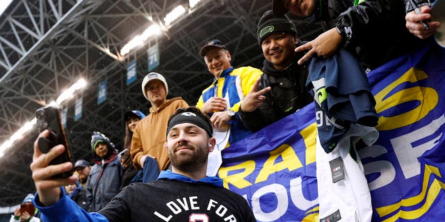 Baker Mayfield #17 de Los Angeles Rams se toma una selfie con los aficionados antes del partido contra los Seattle Seahawks en el Lumen Field el 8 de enero de 2023 en Seattle, Washington.  Mayfield viste una camiseta en honor a Damar Hamlin #3 de los Buffalo Bills. 