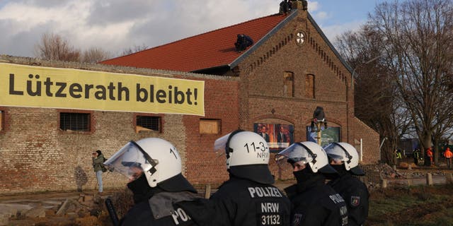 Riot police stand outside a farmhouse in which activists barricaded themselves at the settlement of Luetzerath in Germany.