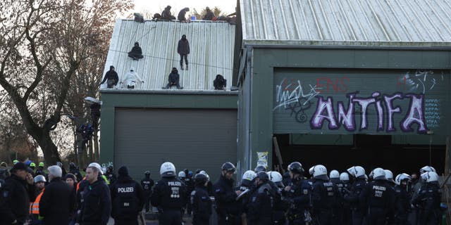 Activists who barricaded themselves in a barn sit on its roof after police entered the building at the settlement of Luetzerath in Germany.