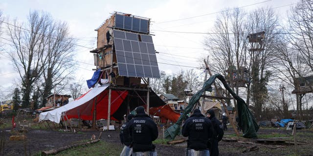 Riot police stand next to a multi-story wooden structure built and still occupied by activists at the settlement of Luetzerath in Germany.