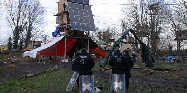 Riot police stand next to a multi-story wooden structure built and still occupied by activists at the settlement of Luetzerath in Germany.