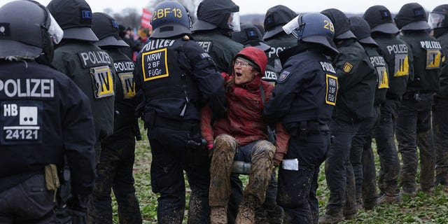 Politie in oproeruitrusting verwijdert een demonstrant tijdens confrontaties nabij de nederzetting Luetzerath op 14 januari 2023 nabij Erkelenz, Duitsland. 