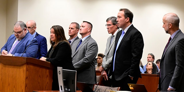Paramedics Peter Cichuniec, fourth from left, and Jeremy Cooper, fifth from left, flanked by their attorneys, left, and prosecutors, right, during an arraignment in the Adams County district court at the Adams County Justice Center January 20, 2023. 