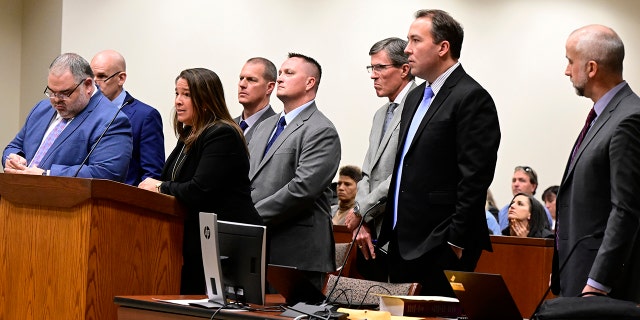 Paramedics Peter Cichuniec, fourth from left, and Jeremy Cooper, fifth from left, flanked by their attorneys, left, and prosecutors, right, during an arraignment in the Adams County district court at the Adams County Justice Center January 20, 2023. 