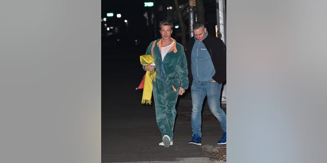 Brad Pitt a également été vu dans une combinaison en velours bleu sarcelle. Il portait une chemise blanche en dessous avec des baskets blanches et portait une écharpe jaune avec un sac rouge sur son épaule.