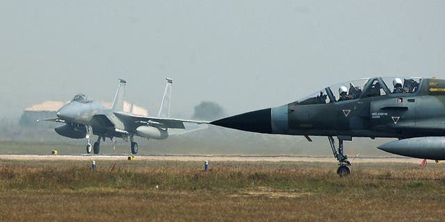 Op deze door de Amerikaanse luchtmacht verstrekte foto staat een M-2000 Mirage van de Indiase luchtmacht te wachten om op de landingsbaan (R) te taxiën terwijl een F-15C Eagle (L) van de Amerikaanse luchtmacht opstijgt in Gwalior, 13 februari 2004.  Luchtmachtbasis in India. 